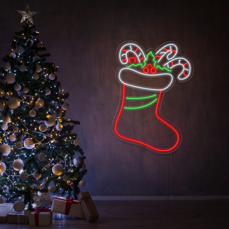 candy cane stocking neon sign hanging on wall next to Christmas tree