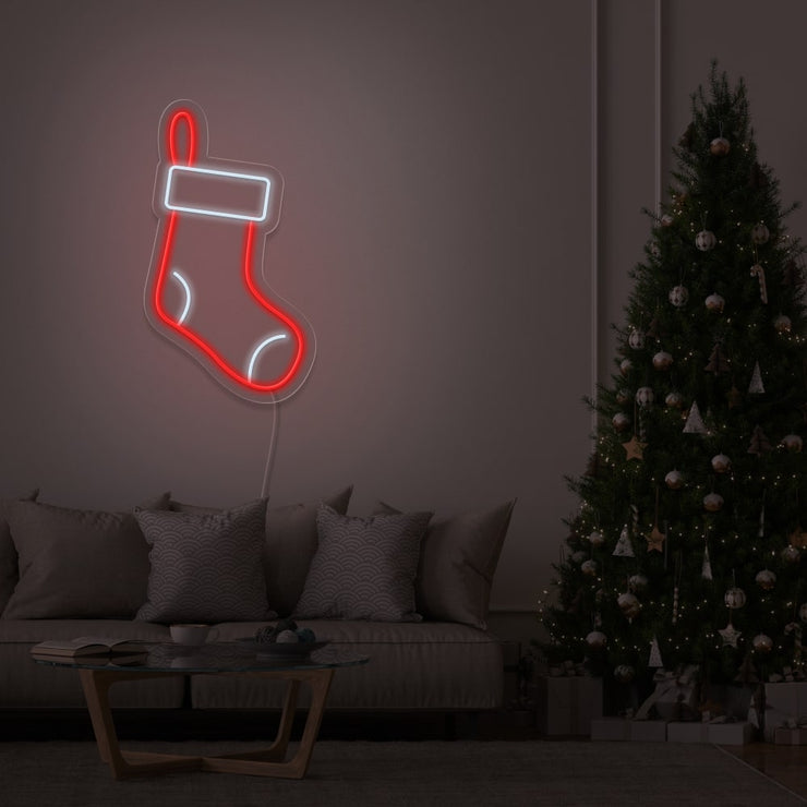 Christmas stocking neon sign hanging on living room wall next to Christmas tree