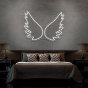 cold white angel wings neon sign hanging on bedroom wall