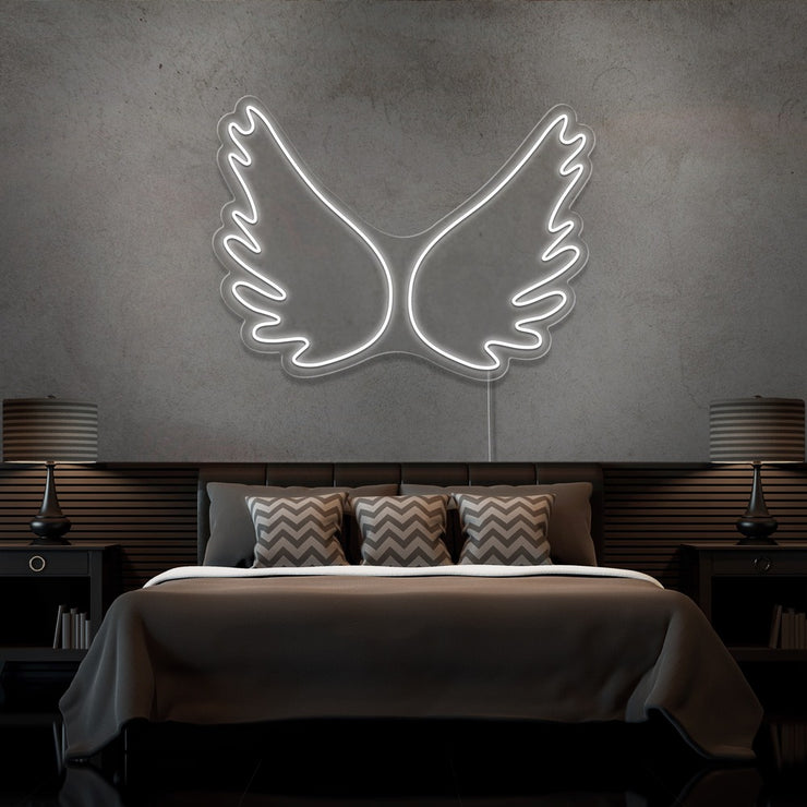 cold white angel wings neon sign hanging on bedroom wall