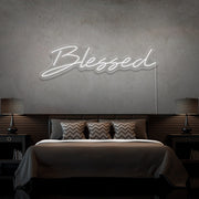 cold white blessed neon sign hanging on bedroom wall