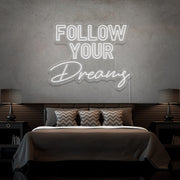 cold white follow your dreams neon sign hanging on bedroom wall