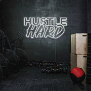 cold white hustle hard neon sign hanging on gym wall
