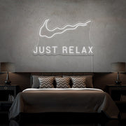cold white just relax neon sign hanging on bedroom wall