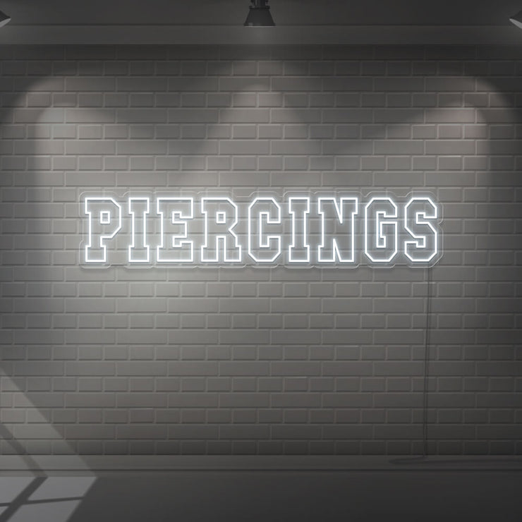 cold white piercings neon sign hanging on wall
