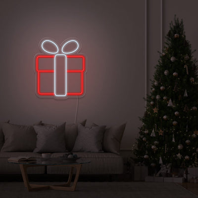 cold white Christmas present neon sign hanging on lounge room wall next to Christmas tree