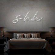 cold white shh neon sign hanging on bedroom wall