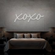 cold white xoxo neon sign hanging on bedroom wall