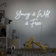 cold white young wild and free neon sign hanging on kids bedroom wall