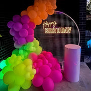 happy birthday neon sign on white mesh backdrop frame with colourful balloons for hire