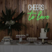 green cheers to love neon sign hanging above dessert table