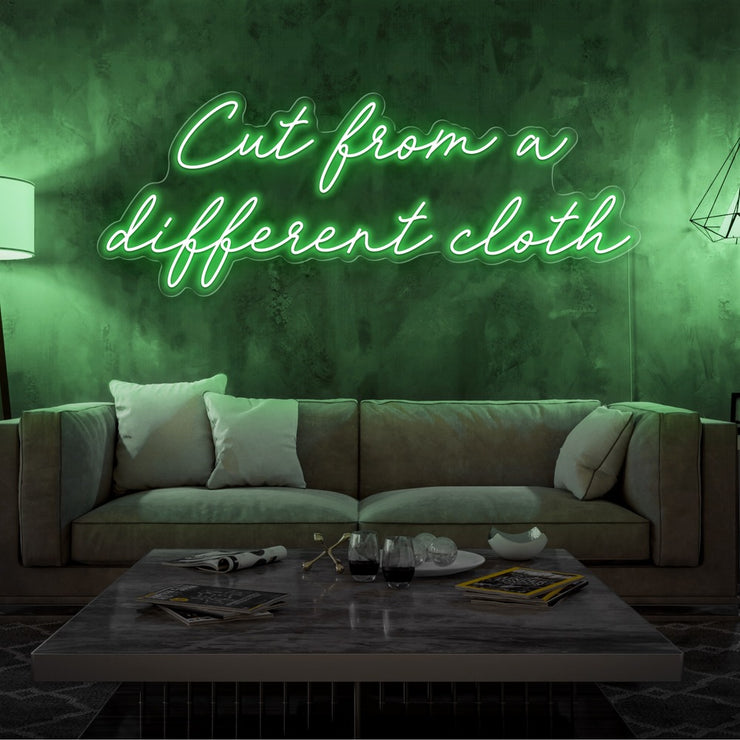 green cut from a different cloth neon sign hanging on living room wall