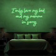 green i only love my bed and my momma im sorry neon sign hanging on bedroom wall