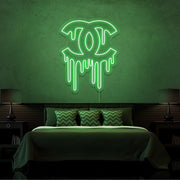 green dripping chanel neon sign hanging on bedroom wall