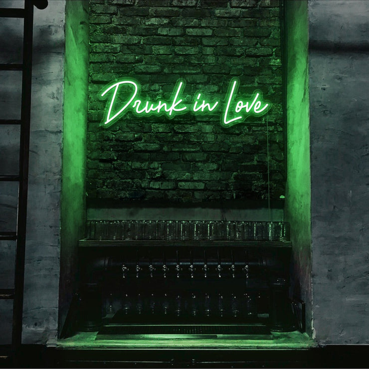 green drunk in love neon sign hanging on bar wall