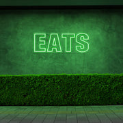 green eats neon sign hanging on outside wall