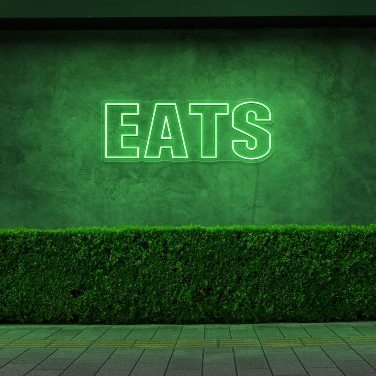 green eats neon sign hanging on outside wall