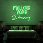 green follow your dreams neon sign hanging on bedroom wall