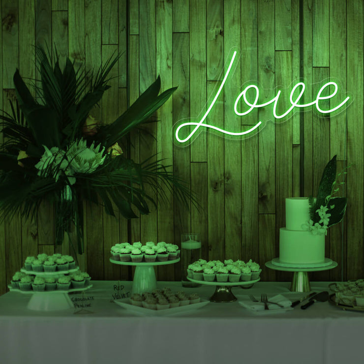 green love neon sign hanging on timber wall above dessert table
