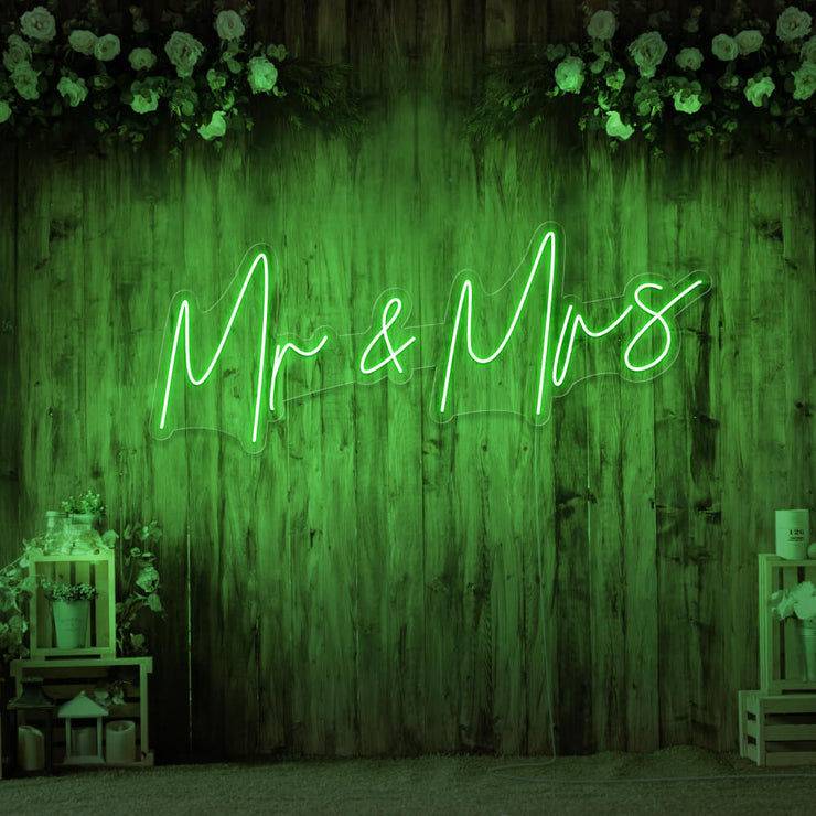 green mr and mrs neon sign hanging on wall with flowers