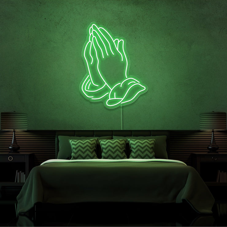 green praying hands neon sign hanging on bedroom wall