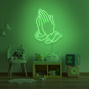 green praying hands neon sign hanging on kids bedroom wall