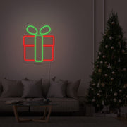 green Christmas present neon sign hanging on lounge room wall next to Christmas tree