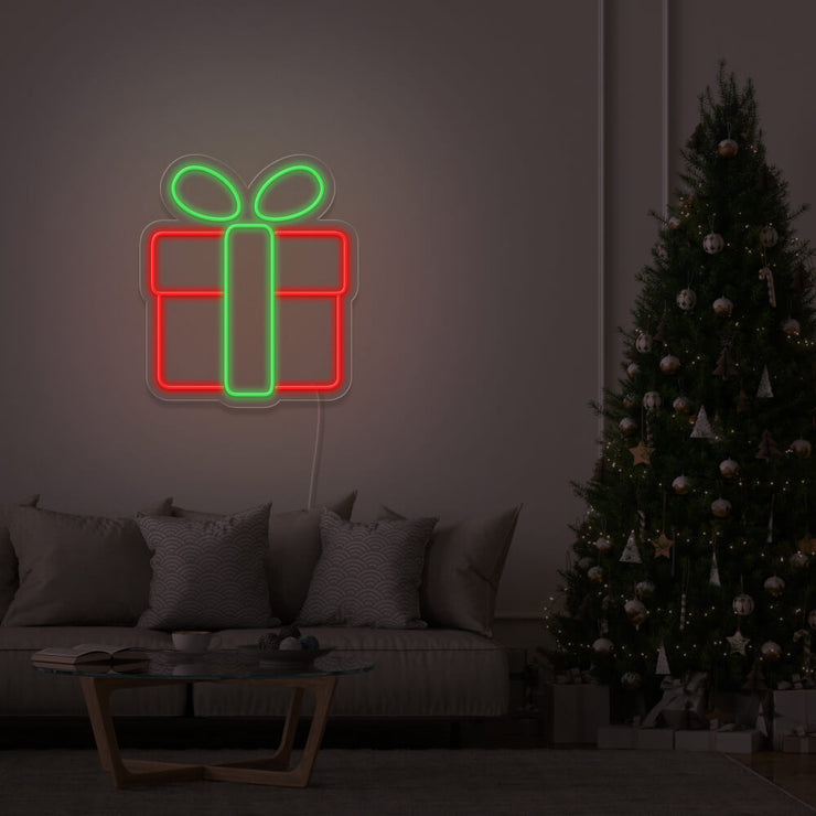 green Christmas present neon sign hanging on lounge room wall next to Christmas tree
