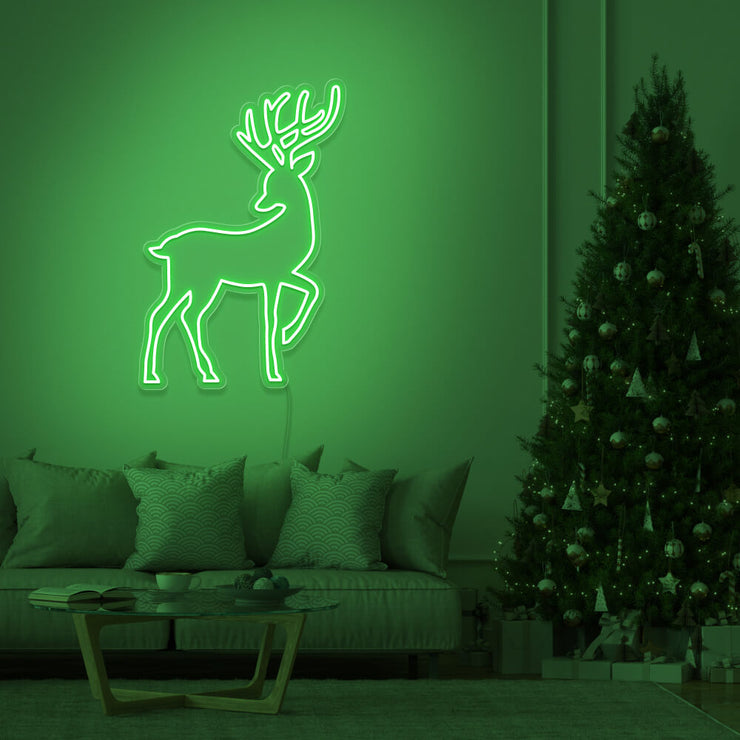 green reindeer neon sign hanging on living room wall next to christmas tree