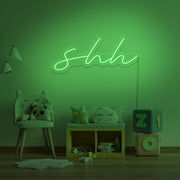 green shh neon sign hanging on kids bedroom wall