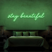 green stay beautiful neon sign hanging on bedroom wall