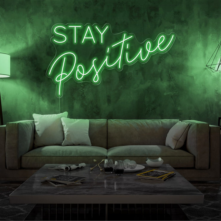 green stay positive neon sign hanging on living room wall