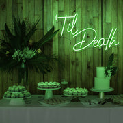 green white til death neon sign hanging on timber wall above dessert table