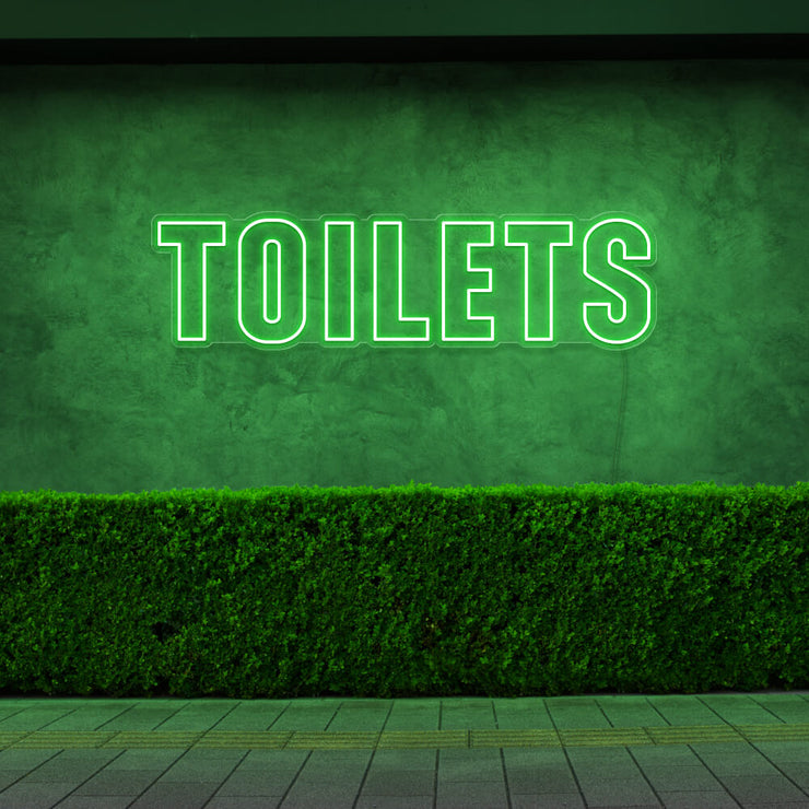 green toilets neon sign hanging on outdoor wall