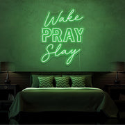 green wake pray slay neon sign hanging on bedroom wall