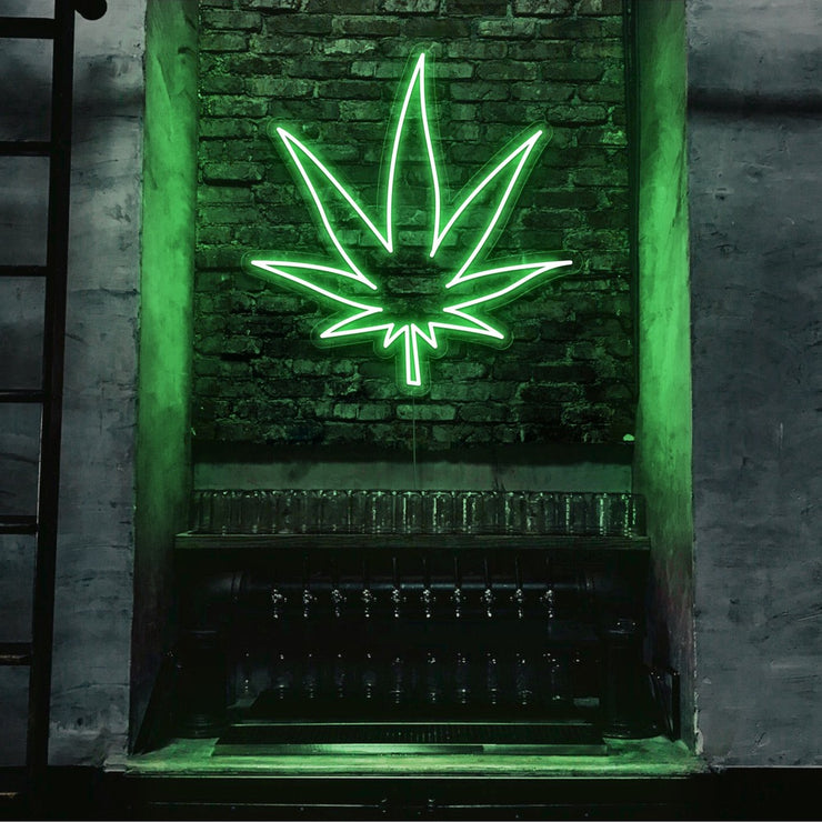 green weed leaf neon sign hanging on bar wall