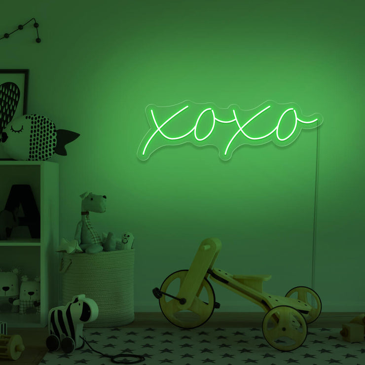 green xoxo neon sign hanging on kids bedroom wall