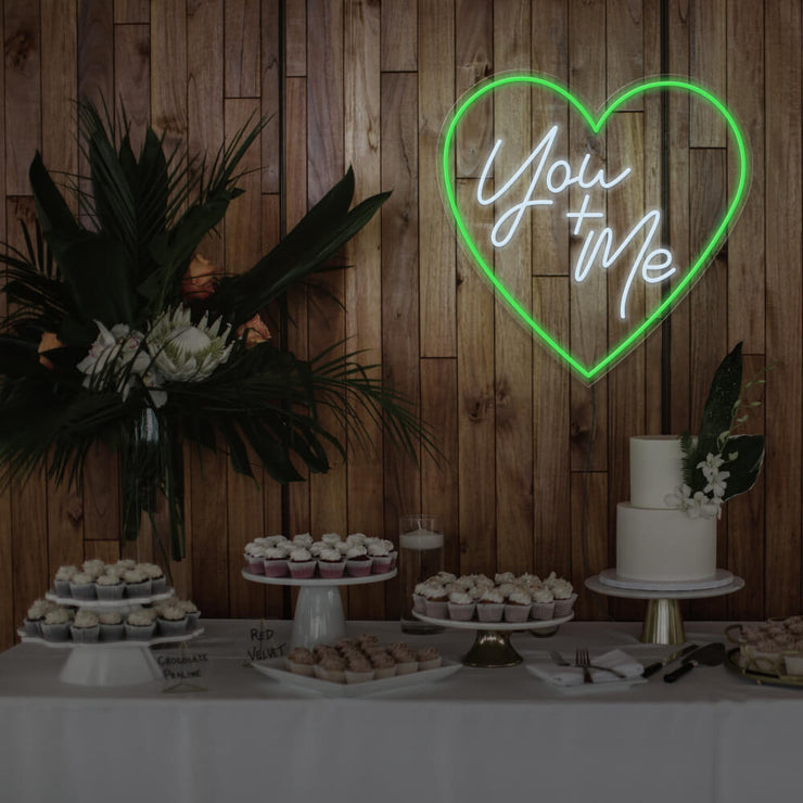 green you and me neon sign hanging on timber wall above dessert table