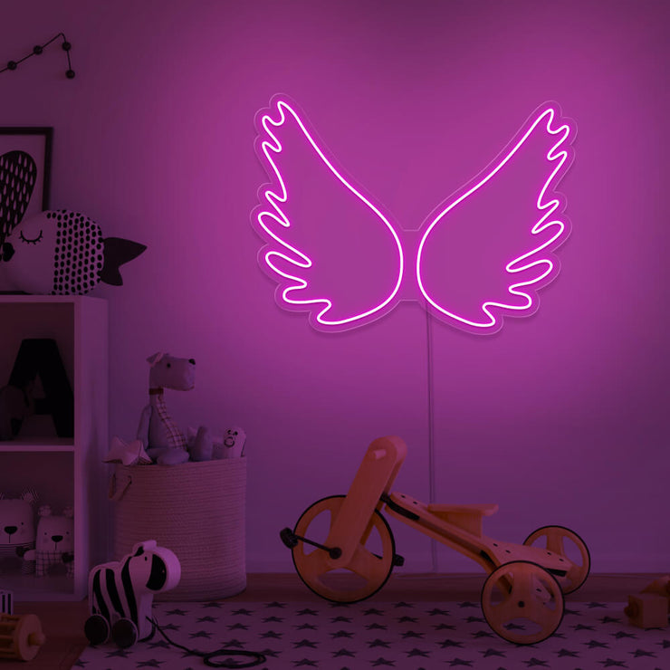 hot pink angel wings neon sign hanging on kids bedroom wall