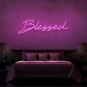 hot pink blessed neon sign hanging on bedroom wall