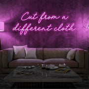 hot pink cut from a different cloth neon sign hanging on living room wall