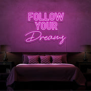 hot pink follow your dreams neon sign hanging on bedroom wall