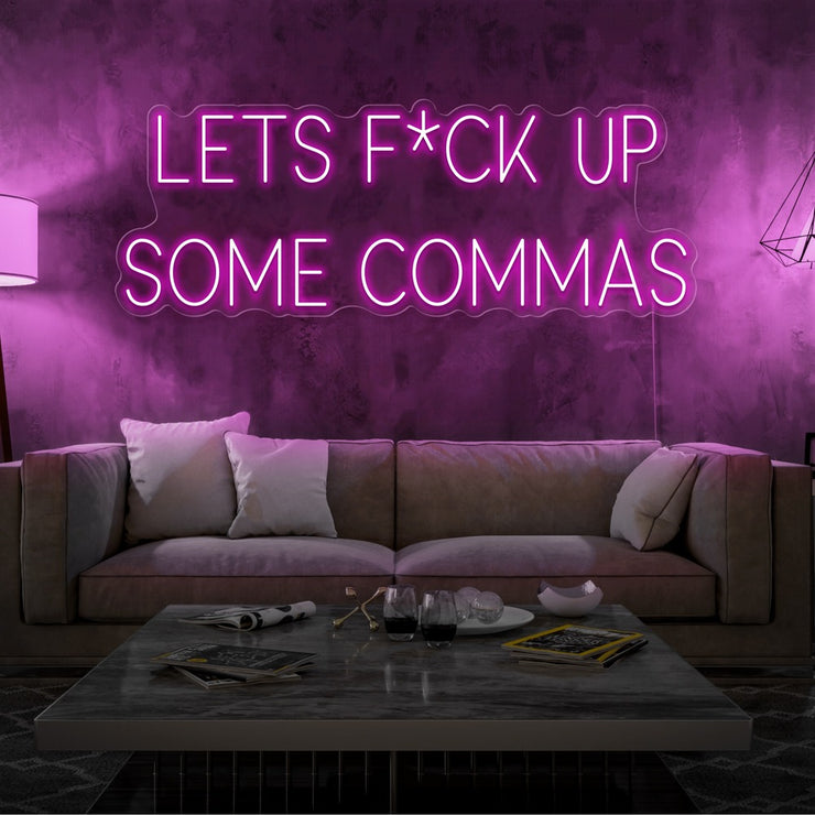 hot pink lets fuck up commas neon sign hanging on living room wall