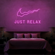 hot pink just relax neon sign hanging on bedroom wall