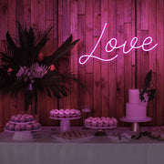 hot pink love neon sign hanging on timber wall above dessert table