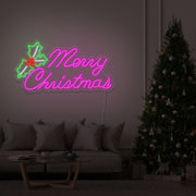 hot pink merry chirstmas mistletoe neon sign hanging above couch next to christmas tree