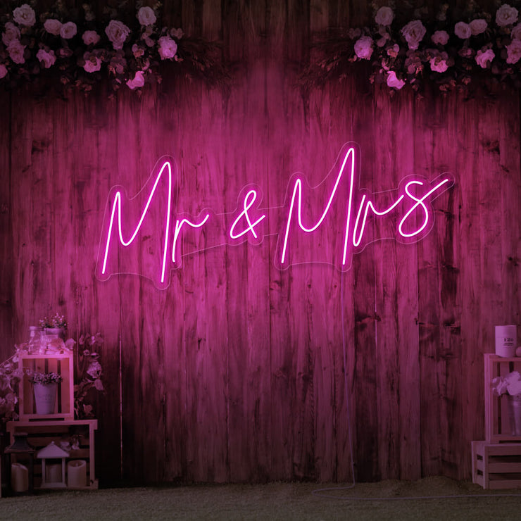hot pink mr and mrs neon sign hanging on wall with flowers