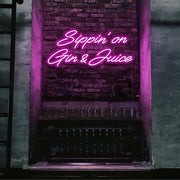 hot pink sippin on gin and juice neon sign hanging on bar wall