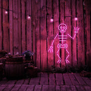 hot pink skeleton neon sign hanging on timber fence