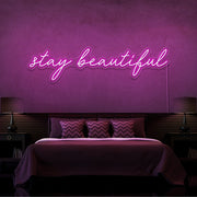 hot pink stay beautiful neon sign hanging on bedroom wall